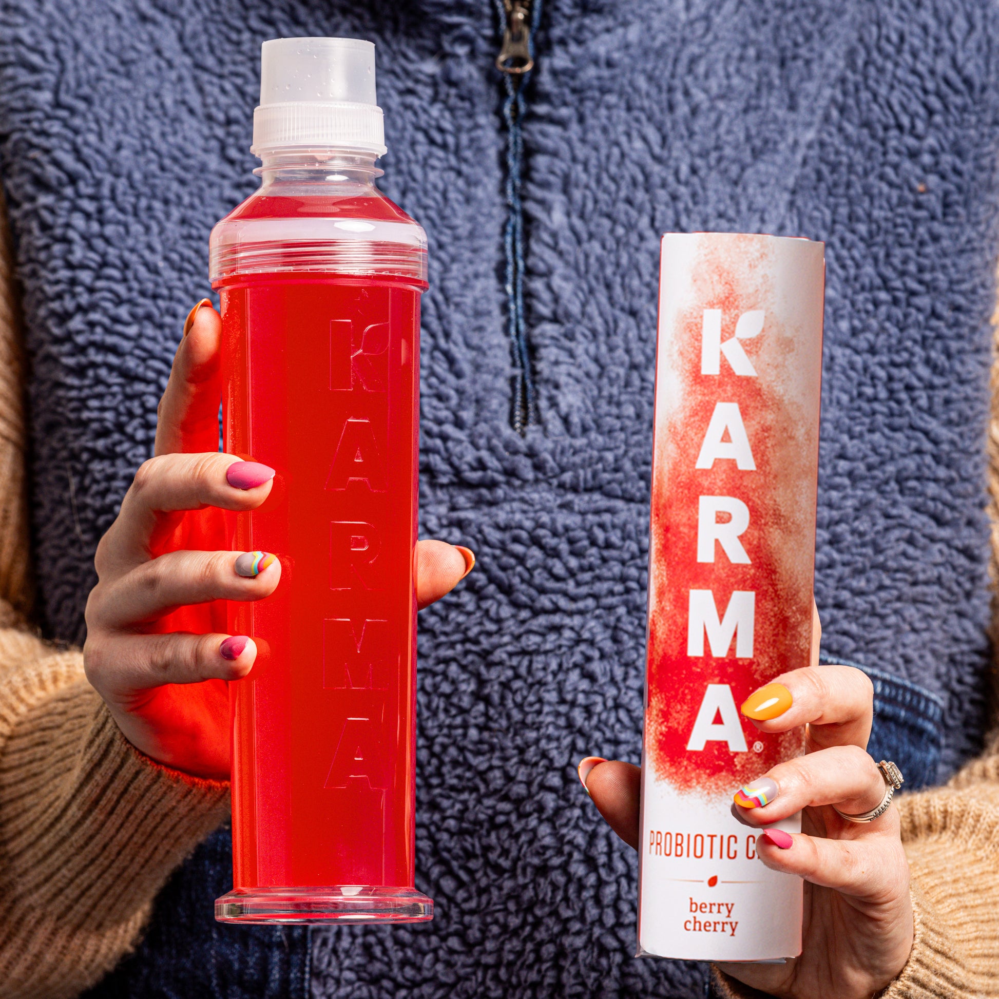 Hands holding a reusable Karma Water Bottle and Probiotic Berry Cherry Caps